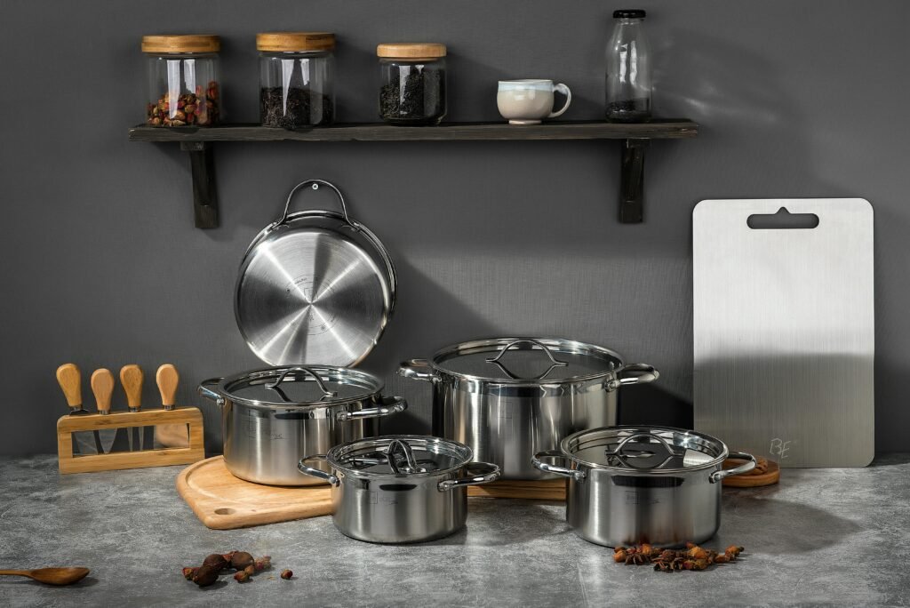 Stylish kitchen setup featuring stainless steel pots and kitchen accessories on a gray background.