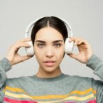 Stylish woman wearing wireless headphones, enjoying music. Captured indoors.