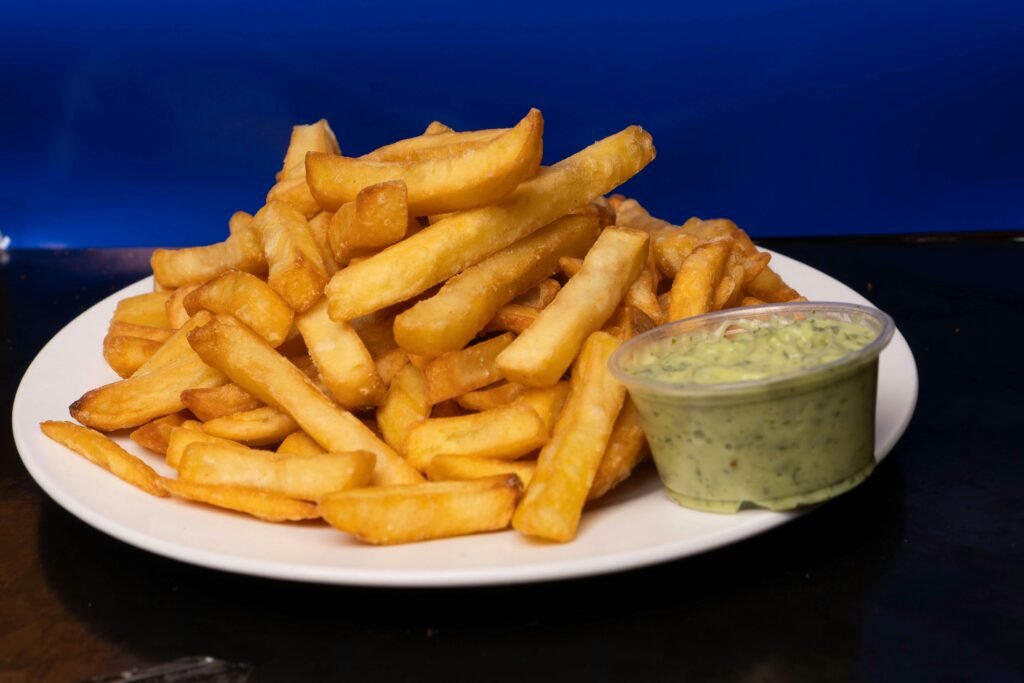Golden crispy french fries served with a rich avocado dip on a white plate. Made With Air Fryer