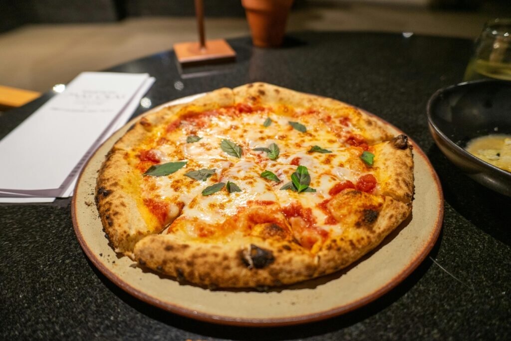 Freshly baked Margherita pizza with basil and mozzarella, served on a stone counter.