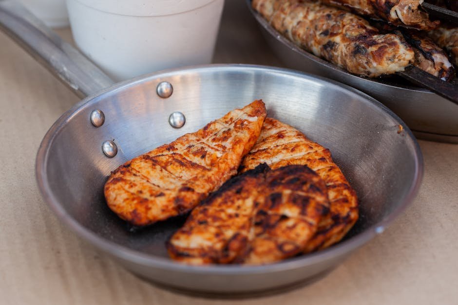 Delicious seasoned chicken breasts grilled and served in a stainless steel pan.